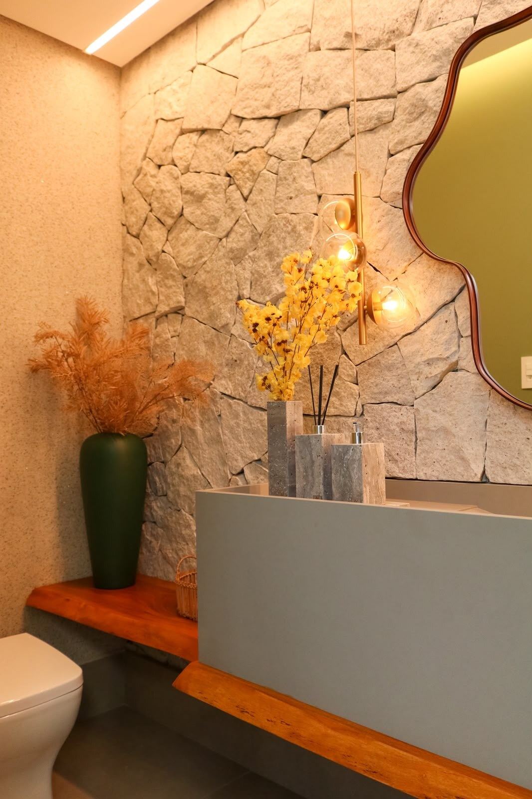Lavabo com parede em pedra, cuba suspensa e vaso decorativo